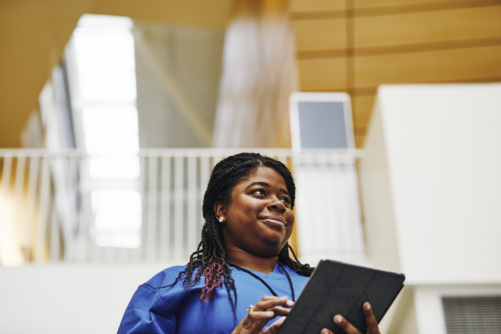 Female nurse using digital tablet in hospital corridor